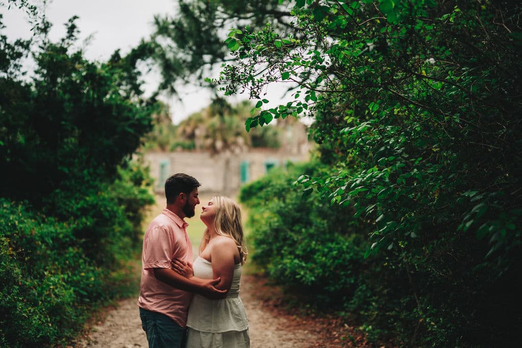 Ella and Zach embracing on a garden path at Huntington Beach State Park