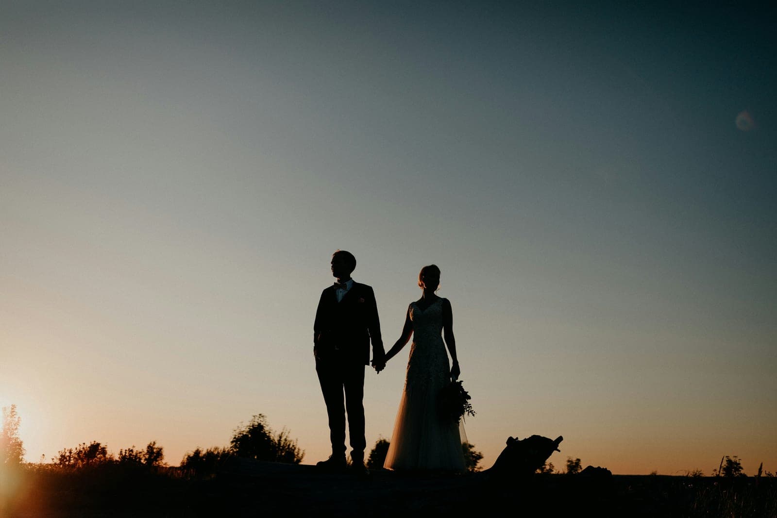 A couple silhouetted against a coastal sunset on their wedding day
